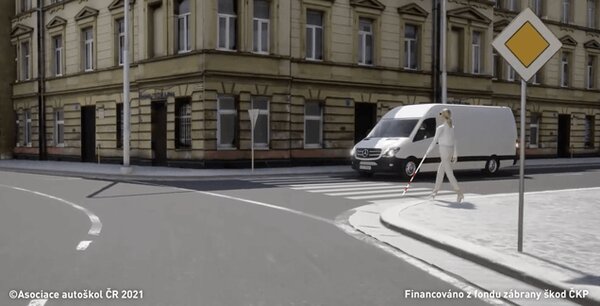 Osoba na přechodu pro chodce označená holí s bílými a červenými pruhy